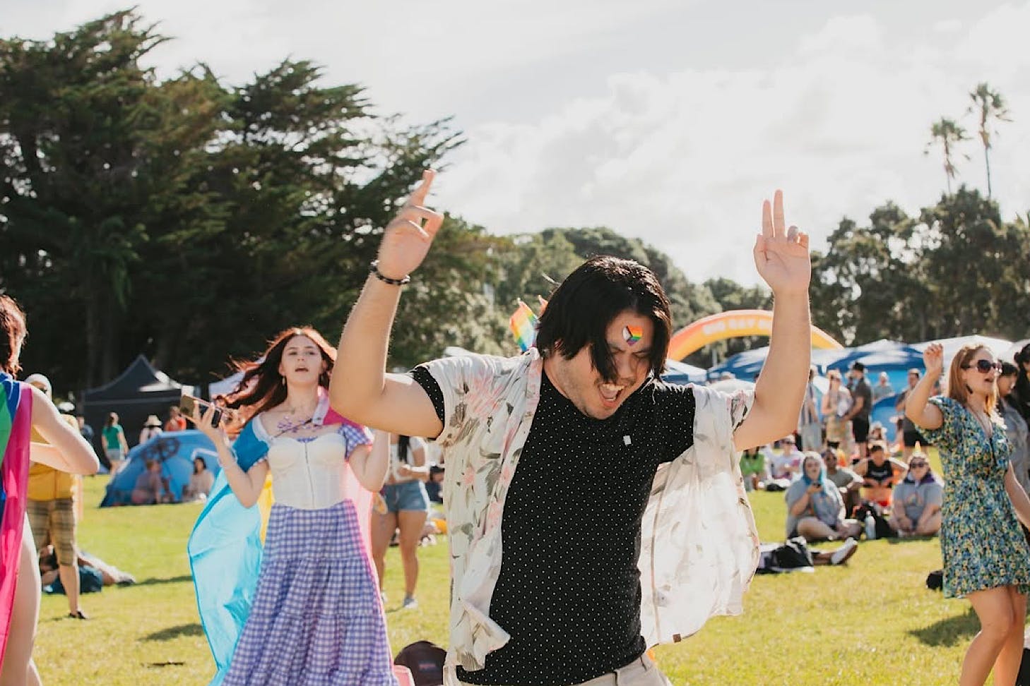 A person with a rainbow flag facepainted on their forehead rocks out to music at Big Gay Out.